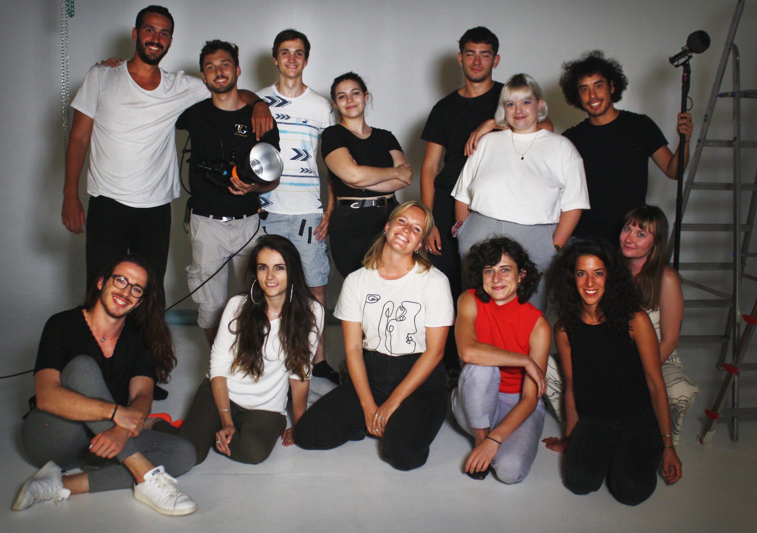 The young people who worked on the new video are posing for a group photo, smiling at the camera. Seven young people stand at the back of the shot with six in a second row in front of them, kneeling. 